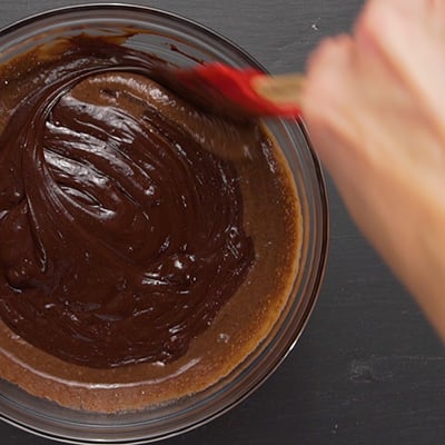 A bowl with melted chocolate and melted ice cream being mixed